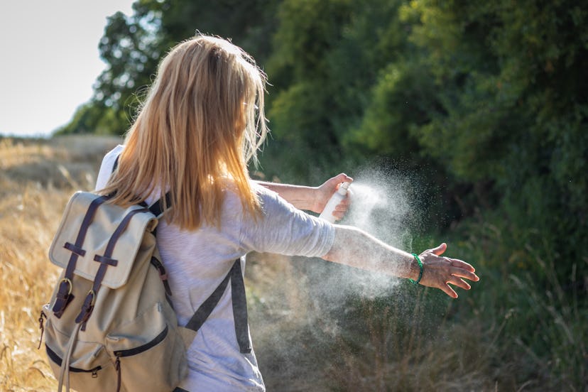 Woman tourist applying mosquito repellent on hand during hike in nature. Insect repellent. Skin prot...