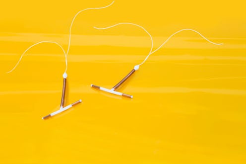 Interauterine coils, or IUDs, on a yellow background, with long strings.