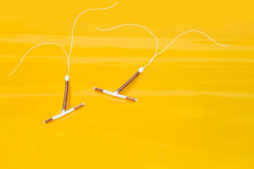 Interauterine coils, or IUDs, on a yellow background, with long strings. 