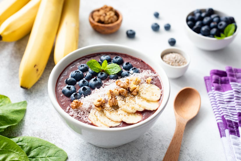 Acai smoothie bowl topped with banana, chia seed, blueberries, walnuts and coconut. Concept of healt...