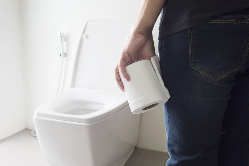 Lady holding tissue near a toilet bowl