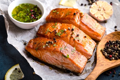 Delicious fried salmon fillet, seasonings on blue rustic concrete table. Cooked salmon steak with pe...