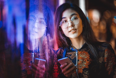 Beautiful mixed race woman posing outdoors, background with blurred neon lights