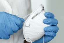 Hands with blue protective nitride gloves holding  N95, FFP2 respirator, face mask. Coronavirus, COV...