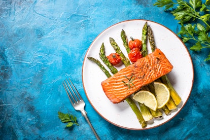 Grilled salmon fish fillet with asparagus. Top view on blue stone table.