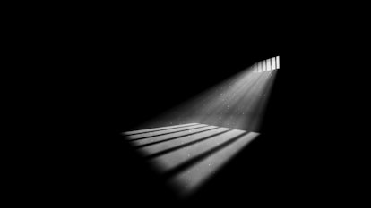 A striking 3d illustration of jail window light in a completely dark prison cell. The rays of sun lo...