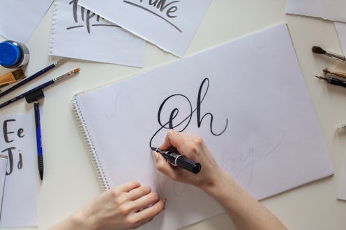 High angle view of Woman hands writing Oh words on white paper