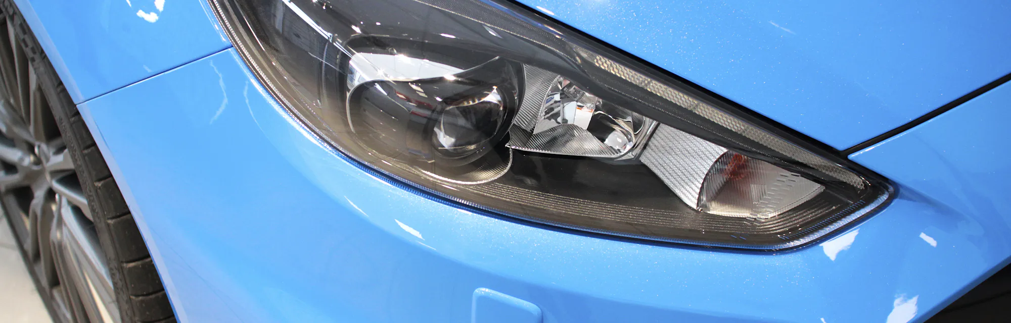 Front light and grill detail from a blue car in saloon