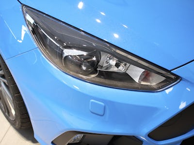 Front light and grill detail from a blue car in saloon