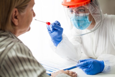 Physician wearing personal protective equipment performing a Coronavirus COVID-19 PCR test, patient ...