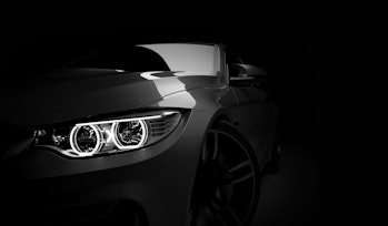 Grey new generic stylish sport coupe car with laser led headlight on dark black background. 3D rende...