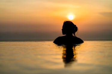 Black silhouette of asian woman on summer vacation holiday relaxing in infinity swimming pool with b...