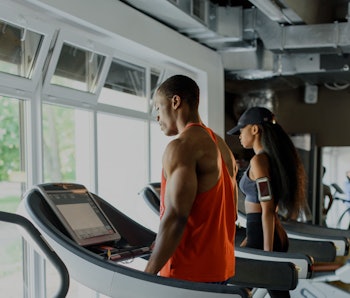 Black african american athletic couple running on treadmills in gym