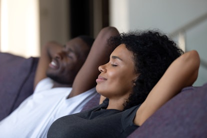 Relaxed african couple enjoying peaceful rest breathing fresh air at home on comfortable couch, happ...
