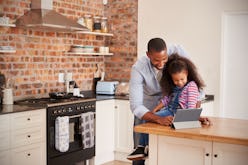 Father And Daughter Using Digital Tablet In Kitchen At Home