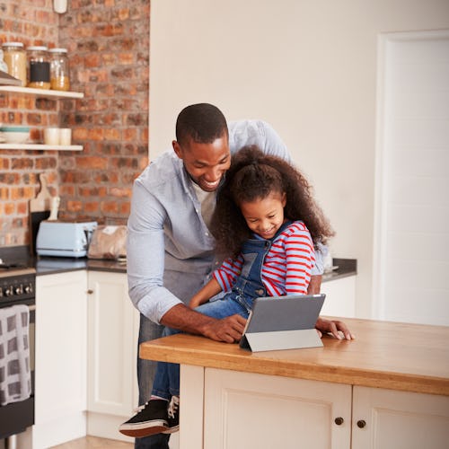 Father And Daughter Using Digital Tablet In Kitchen At Home