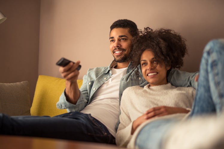 Photo of a young african american family relaxing by the television at home.