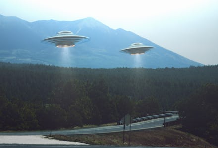 Unidentified flying object. Two UFOs flying over a road among the trees. 3D illustration.