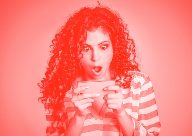 Shocked look at phone. Closeup portrait surprised young girl looking at phone seeing bad news or pho...