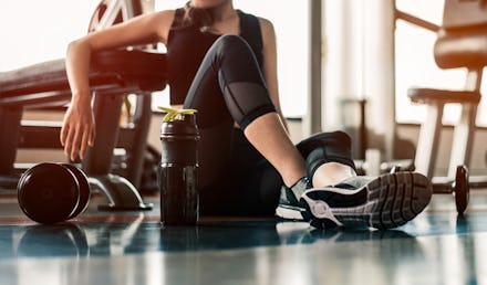 Fitness woman Relaxing after exercise with a whey protein and dumbbell placed beside the gym.Relaxi...