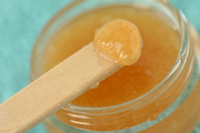 Macro of homemade lip scrub made out of brown sugar, honey and olive oil in a glass jar