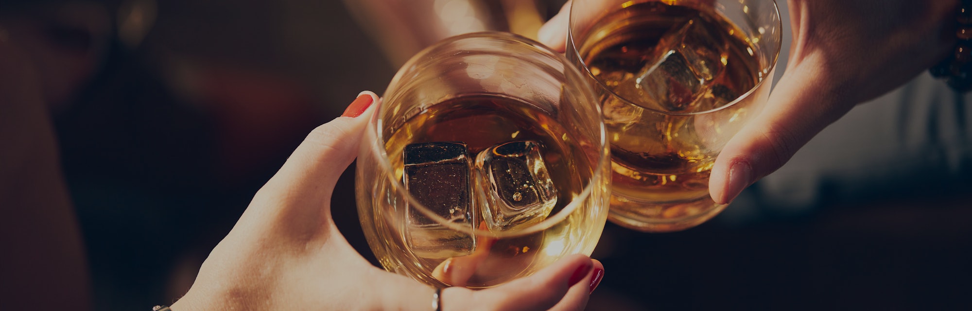 A couple makes a toast with two glasses of whiskey