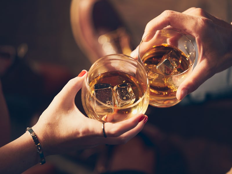 A couple makes a toast with two glasses of whiskey