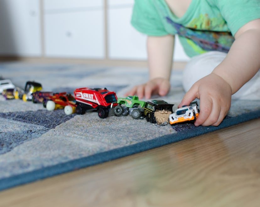 Child lining up toys on the floor at home.