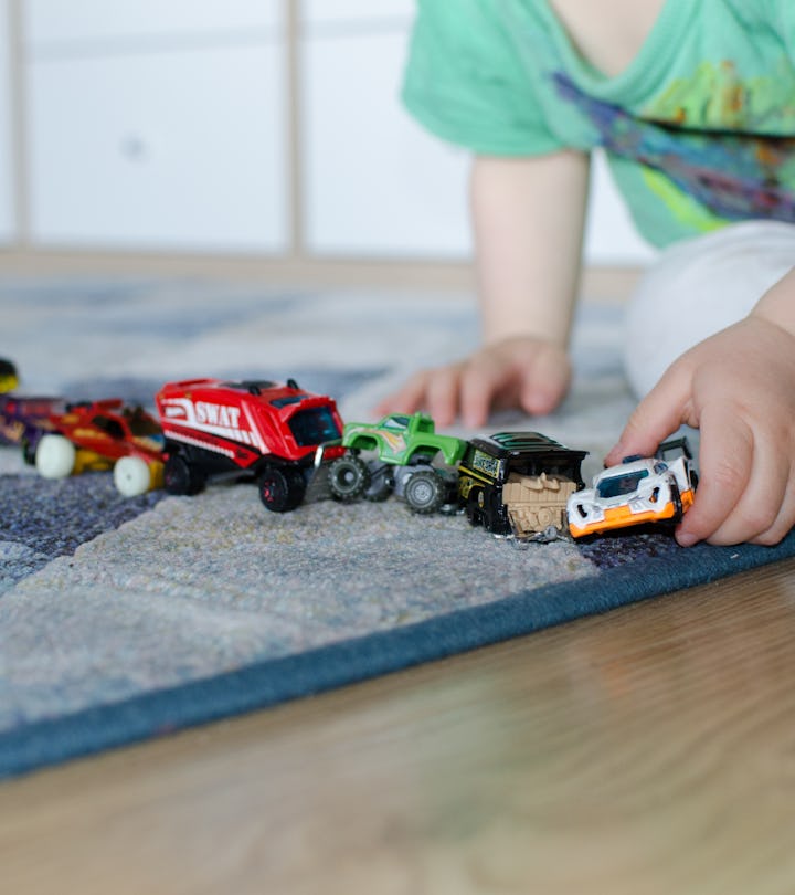 Child lining up toys on the floor at home.