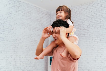 A dad gives carries his young daughter on his shoulders.