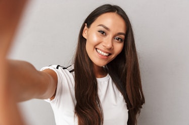 Image of excited happy young woman isolated over grey background make selfie by camera.