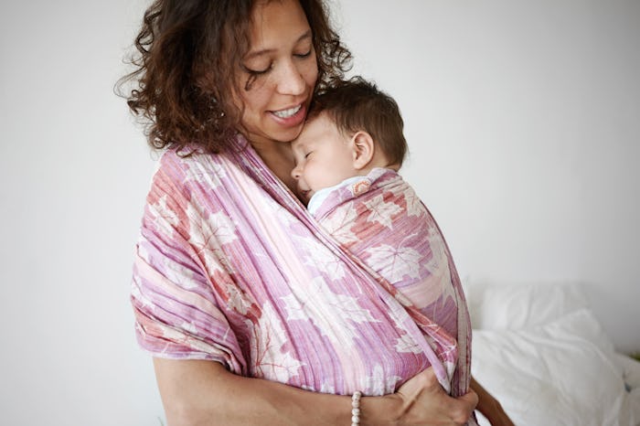 Indoor shot of beautiful young mixed race mother smiling, watching her adorable newborn infant son s...