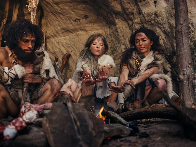 Tribe of Prehistoric Hunter-Gatherers Wearing Animal Skins Live in a Cave at Night. Neanderthal or H...