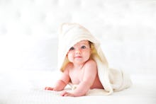 Six month baby wearing towel after bath. Childhood and baby care concept