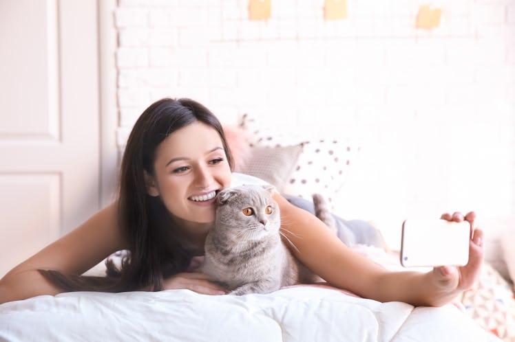 A happy woman takes a selfie with her cat. 