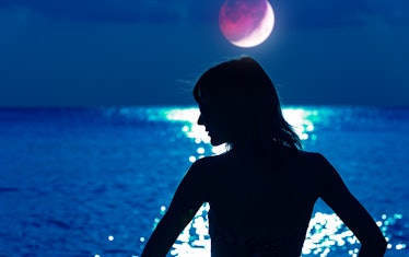Silhouette of a woman with distant ocean horizon at night.