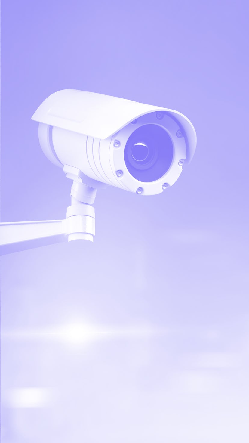 Modern CCTV camera on a wall. A blurred night cityscape background. Concept of surveillance and moni...