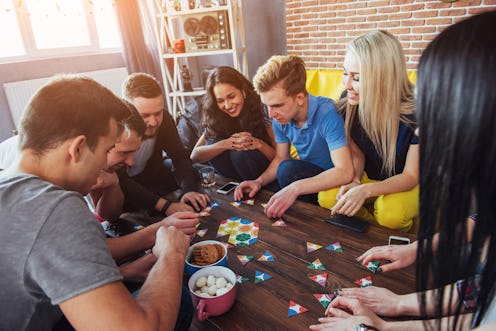 Group of creative friends sitting at wooden table. People having fun while playing board game.