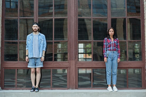 Serious hipster couple stands near building