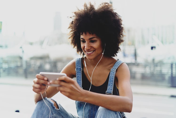 charming black girl with a charming smile book tickets online via cellphone.a young woman with beaut...