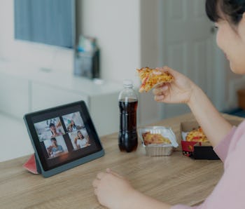 Asian woman virtual happy hour meeting party and eating food online together with her friend in vide...