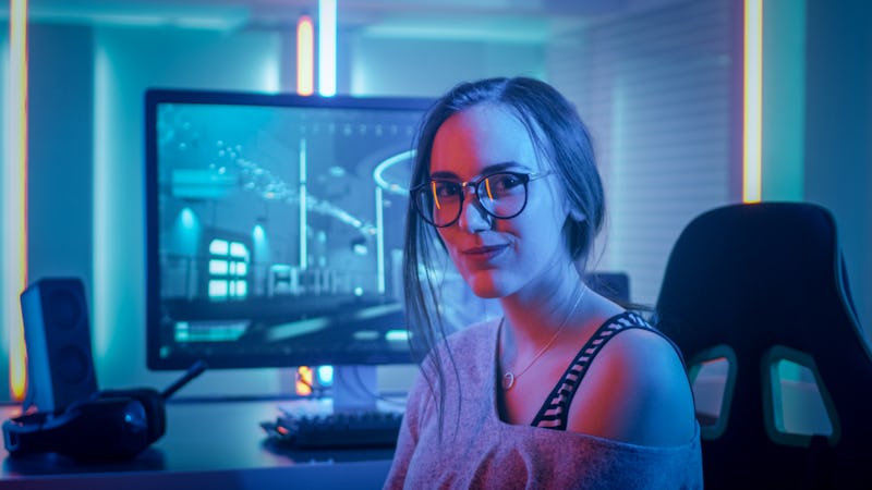 Portrait of the Beautiful Young Pro Gamer Girl Sitting at Her Personal Computer and Looks into Camer...