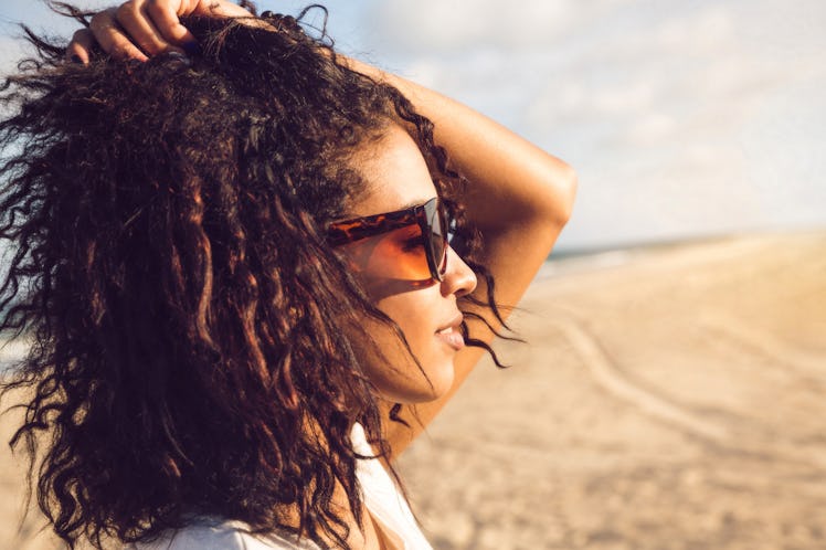 Side view portrait of a young afro american woman in sunglasses enjoying sun on a beach