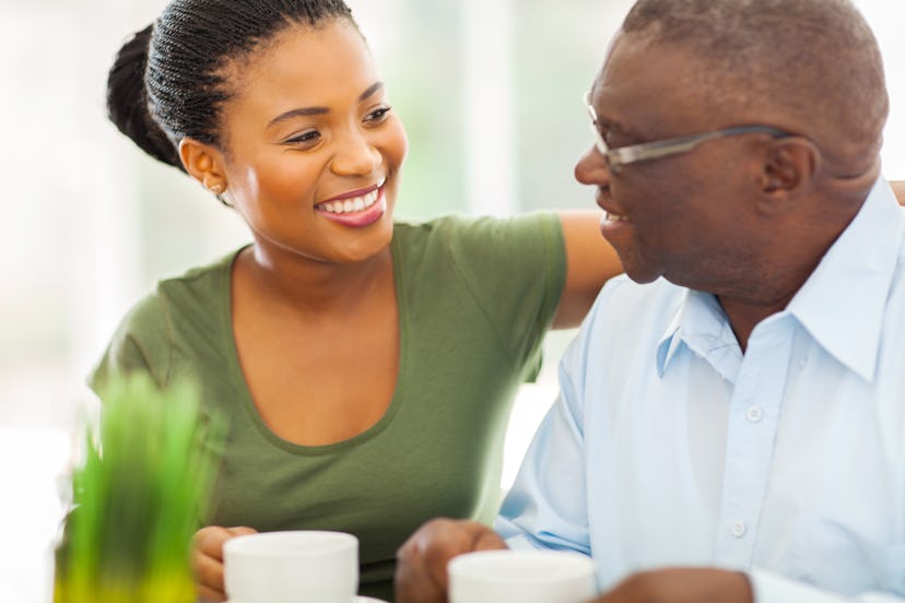 smiling elderly african american man enjoying coffee with his granddaughter at home