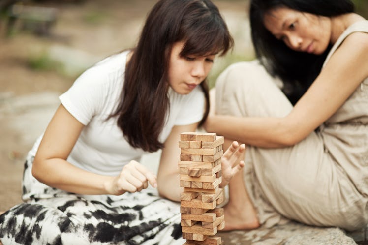 A woman pulls a block out of a Jenga tower outside.