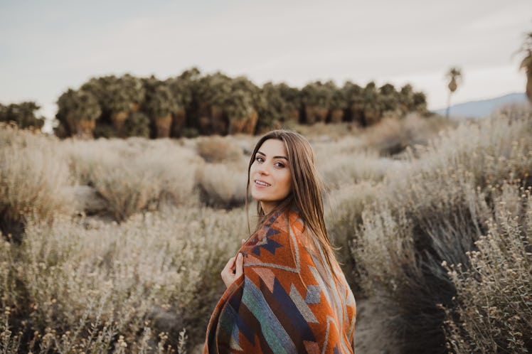 Smiling, beautiful hipster traveler girl in gypsy look and windy hair, in desert nature. Artistic p...