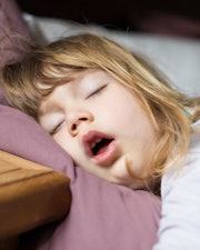 funny face expression with open mouth of blonde caucasian three years old child,  sleeping on  king ...