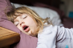 funny face expression with open mouth of blonde caucasian three years old child,  sleeping on  king ...