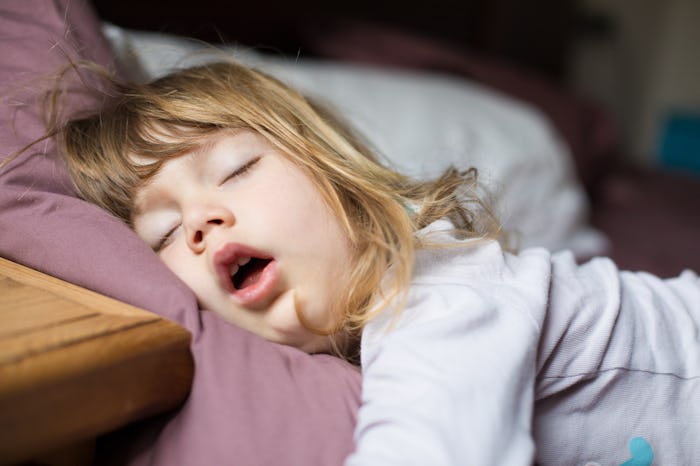 funny face expression with open mouth of blonde caucasian three years old child, sleeping on king ...