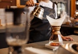 Professional barista preparing coffee using chemex pour over coffee maker and drip kettle. Alternati...